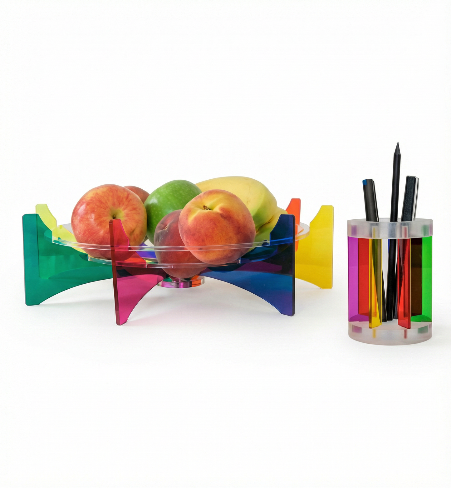 Colorful fruit bowl with apples and a holder with pens on a white background