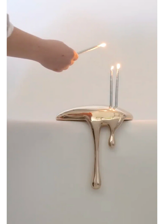 Gold candle holder with a candle being lit on a white background