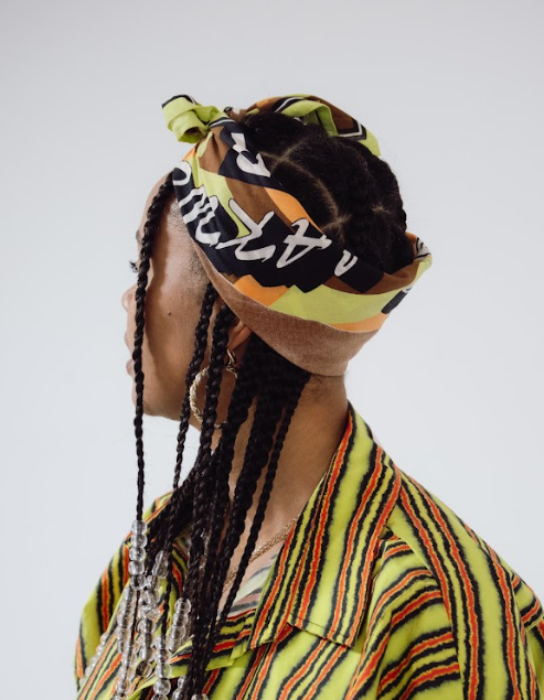 Person wearing a colorful headscarf and striped shirt against a white background