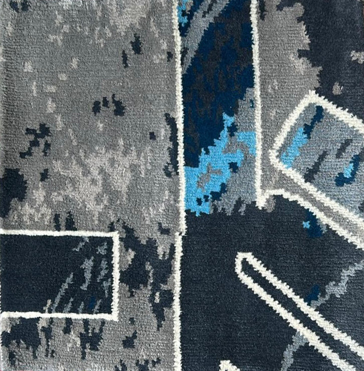 Close-up of a patterned rug with geometric shapes in gray, blue, and black.