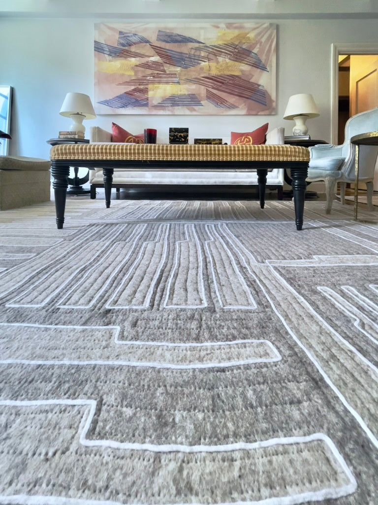 Living room with a patterned rug, coffee table, and abstract painting on the wall.