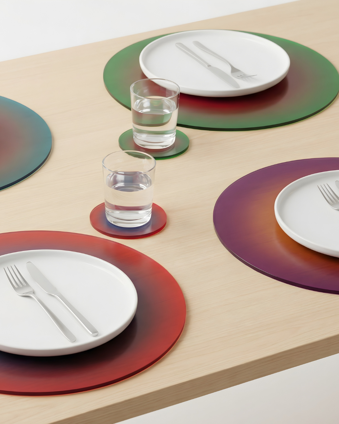 Colorful placemats with plates, glasses, and cutlery on a wooden table.