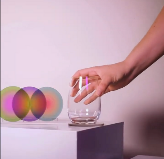 Hand reaching towards a clear glass object with colorful blurred circles in the background