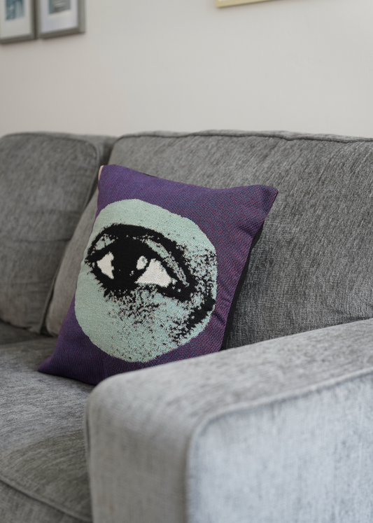 Decorative pillow with an eye design on a gray couch