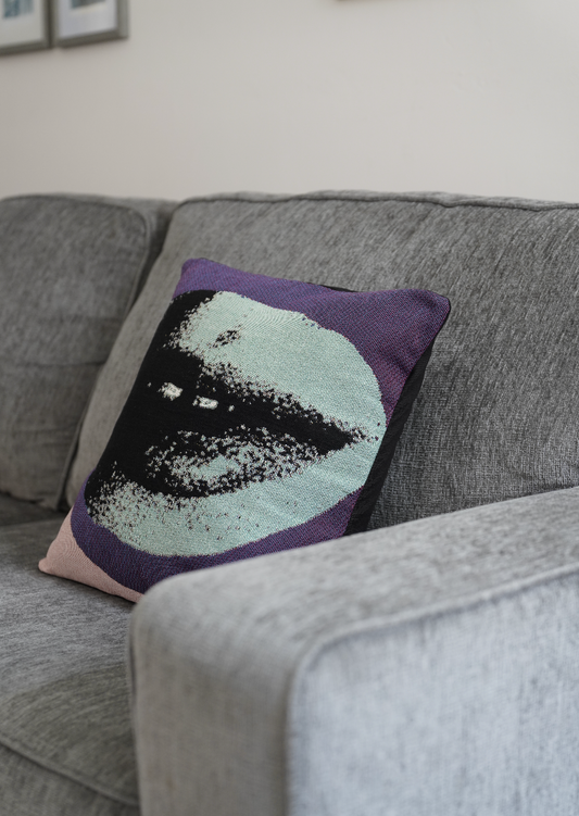 Decorative pillow with a face design on a gray sofa