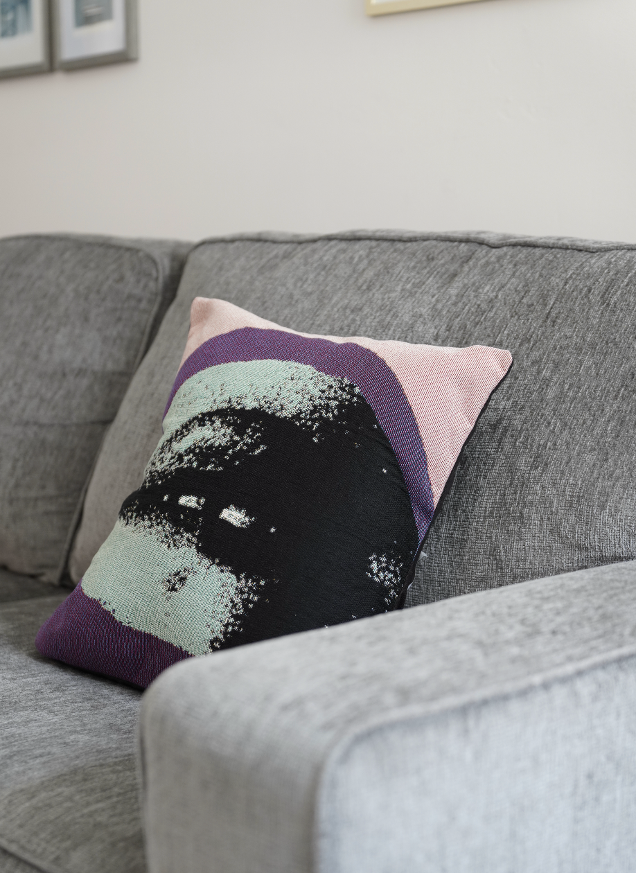 Decorative pillow with a black cat design on a gray sofa