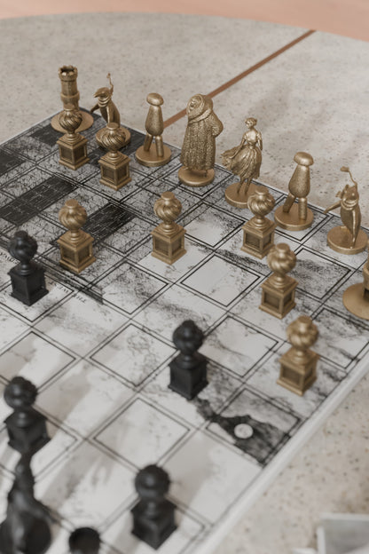 Close-up of a chessboard with gold and black pieces on a textured surface.