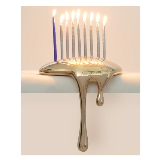 A gold menorah with a continuous drip design, featuring lit candles on its branches, placed against a plain background.