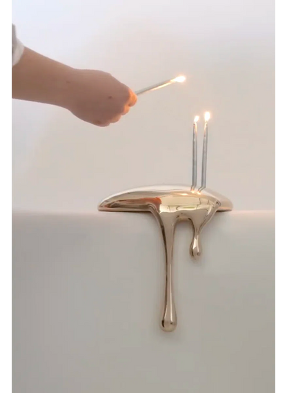 Gold candle holder with a candle being lit on a white background