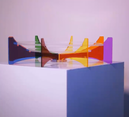 Colorful geometric sculpture on a white platform with a white background