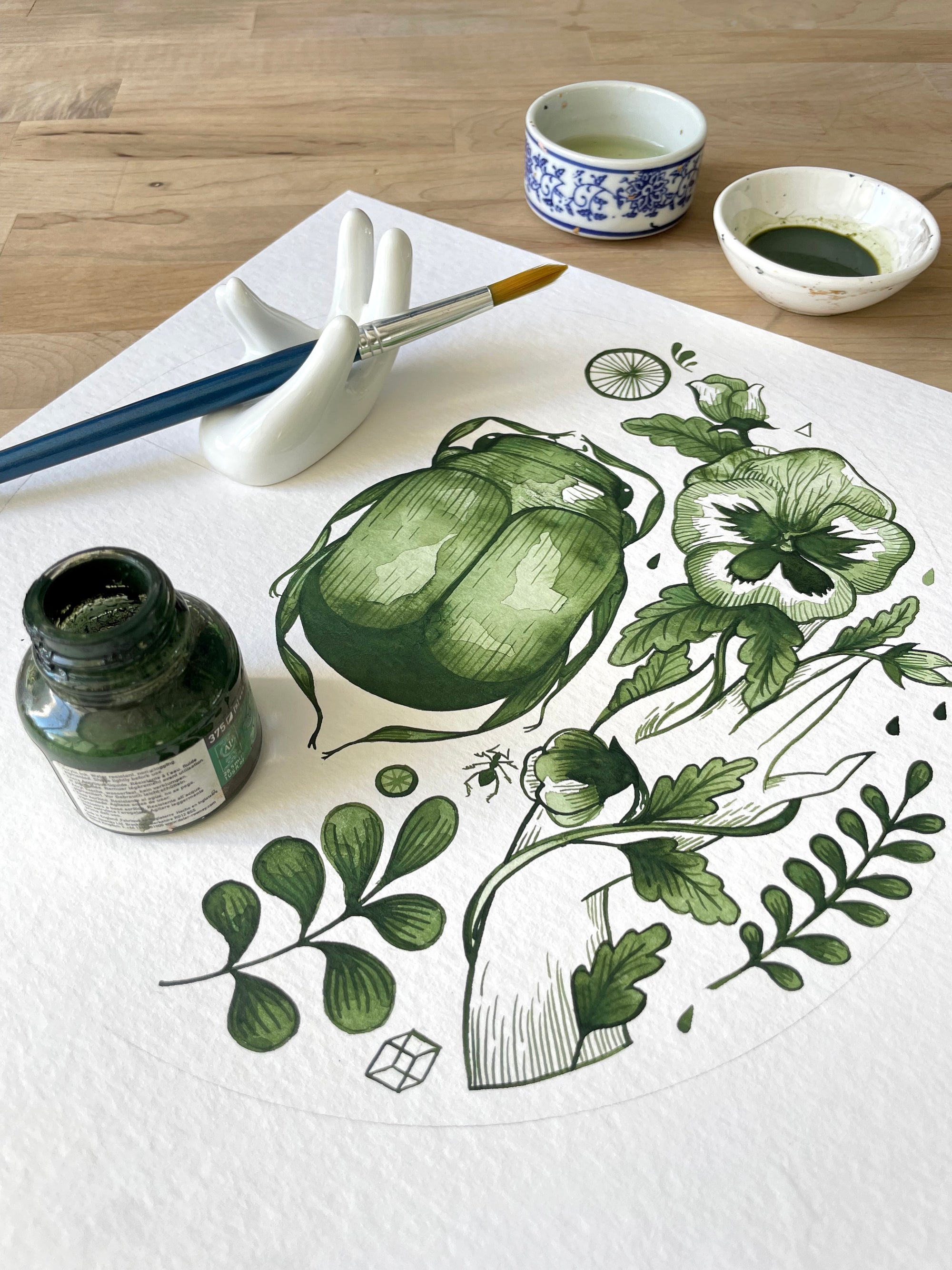 Decorative bowl with green leaf pattern on a white background and gold accents