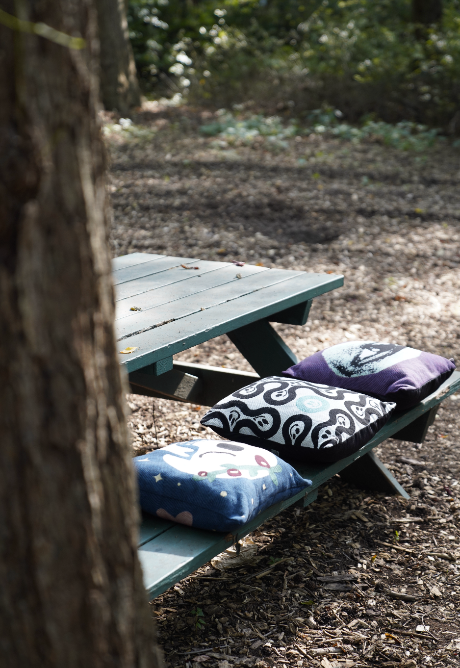 Wooden picnic table with patterned cushions in a forest setting