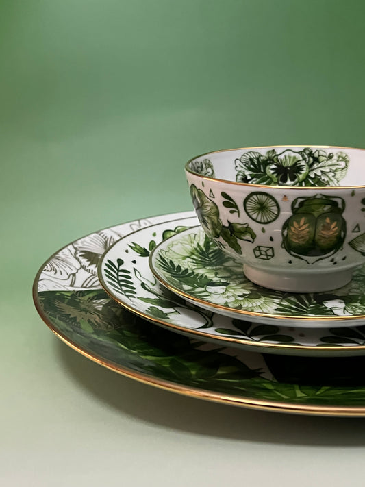 Tea cup and saucer with green botanical design on a green background