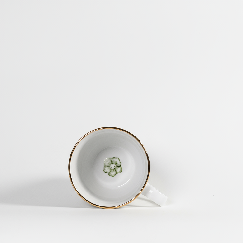 White teacup with gold rim and floral design on a white background