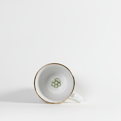 White teacup with gold rim and floral design on a white background