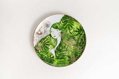 Decorative plate with a green leaf pattern and a face design on a white background