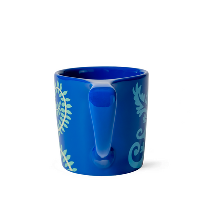 Blue mug with white handle and green leaf patterns on a white background