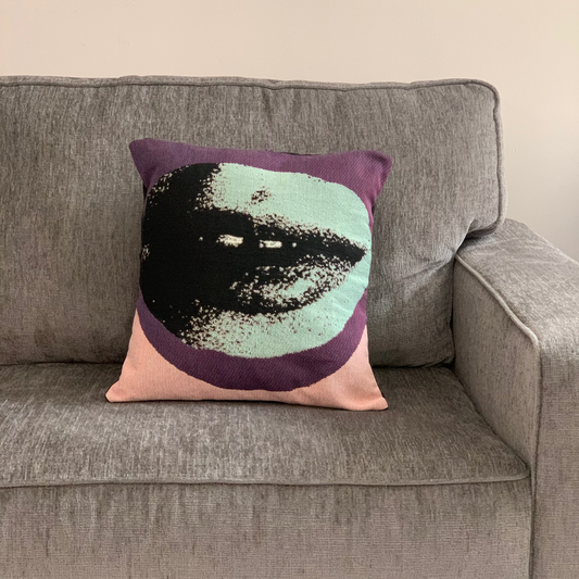 Decorative pillow with a face design on a gray couch