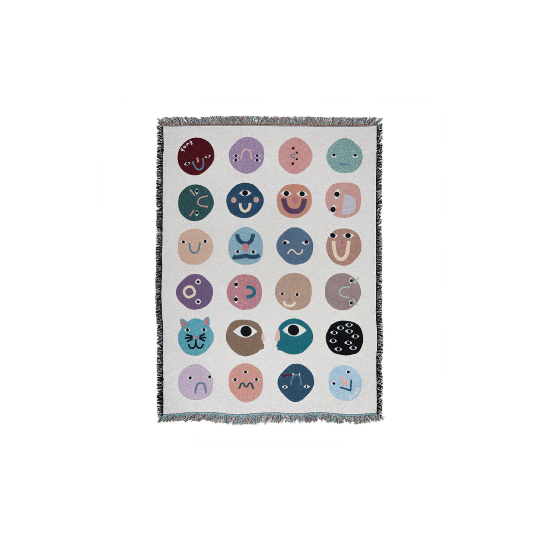 Blanket with colorful emoji-like face patterns on a white background