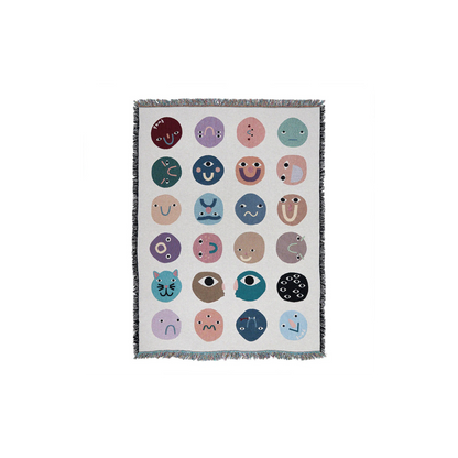 Blanket with colorful emoji-like face patterns on a white background