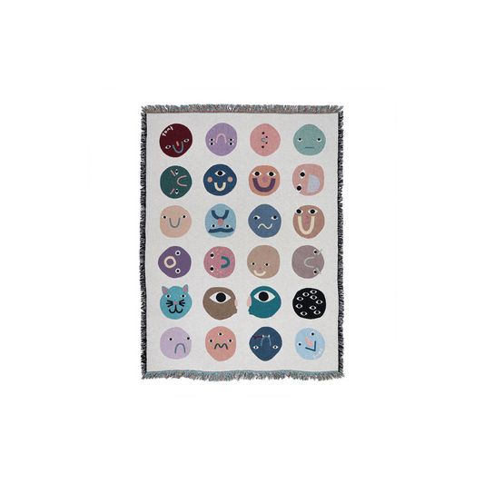 Blanket with colorful emoji-like face patterns on a white background